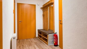 Ein Korridor mit Holzboden, einer Bank, einem Feuerlöscher und einer Tür.