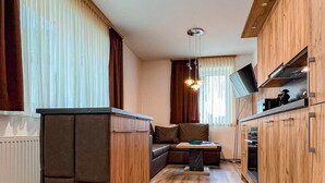 Eine moderne Küche mit Holzschränken, einem eingebauten Ofen und einem Essbereich mit einer Couch und einem Tisch.