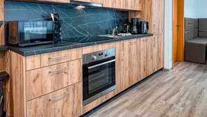 Eine moderne Küche mit Holdekor-Schränken, einer schwarzen Arbeitsplatte und einem eingebauten Backofen.