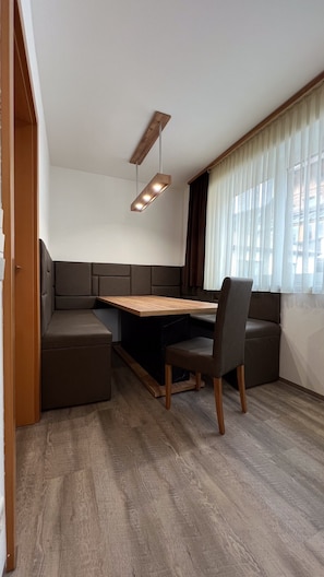 A modern kitchen with a wooden table, built-in seating, and a pendant light.