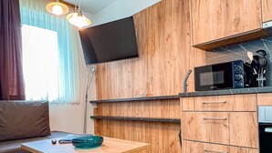 Eine moderne Küche mit Holzschränken, einer Mikrowelle und einem Essbereich mit Tisch und Stühlen.