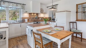 A modern kitchen with wooden countertops, a central island, and a dining area with a wooden table and chairs.