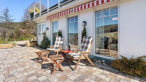 A patio with outdoor furniture, a glass door, and a view of the surrounding landscape.
