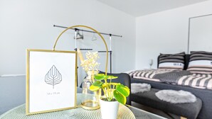 A framed artwork, a potted plant, and a bed in a modern room.