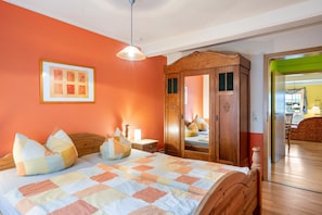 Quarto com cama, guarda-roupa de madeira, espelho e quadro na parede.