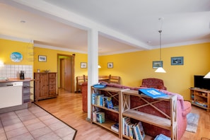 Uma sala de estar com sofá, estante, armário de madeira e televisão.