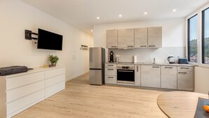 Eine moderne Küche mit Backofen, Kühlschrank und einem flachbildfernseher an der Wand.