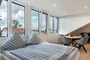 Ein modernes Schlafzimmer mit einem großen Bett, einem kleinen Tisch und zwei Stühlen.