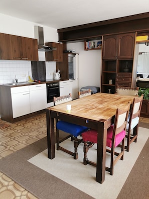 A modern kitchen with wooden cabinets, a dining table with chairs, and a built-in oven.