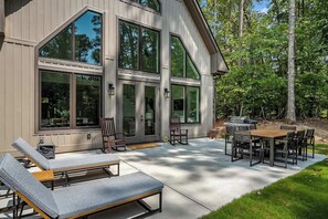 A modern house with a patio area featuring outdoor furniture and a grill.