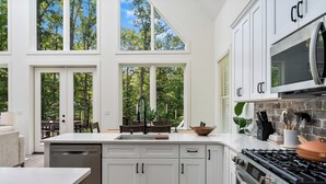 A modern kitchen with white cabinetry, a large island with a sink, and a gas stove. - Clemson Cove - Beautiful new construction on outskirts of Clemson! (Central)