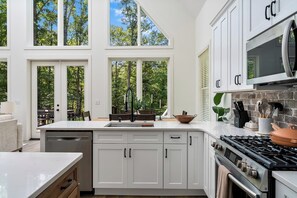 A modern kitchen with white cabinetry, a large island with a sink, and a gas stove.