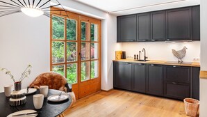 Una cocina moderna con armarios oscuros, una mesa de comedor de madera y un gran ventanal.