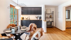 Una cocina moderna con armarios oscuros, una mesa redonda para comer y un perro.