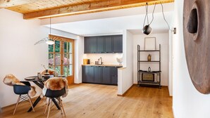 Una cocina moderna con armarios oscuros, techo de madera y un comedor con sillas y una mesa.