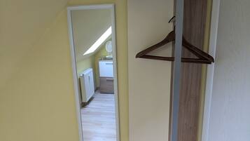 A room with a wooden floor, a white door, and a mirror on the wall.