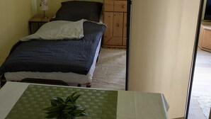 A bedroom with a bed, a dresser, a lamp, and a plant.