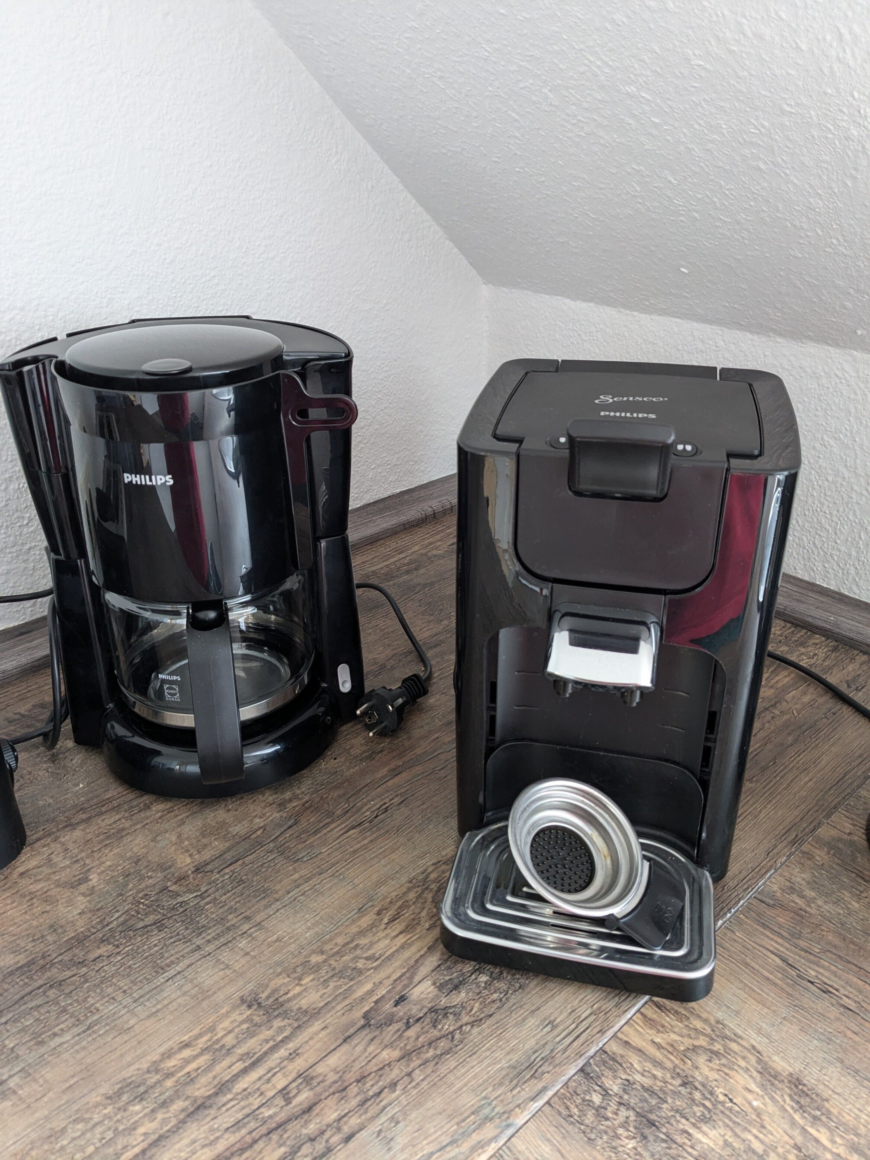Two coffee makers on a wooden surface.