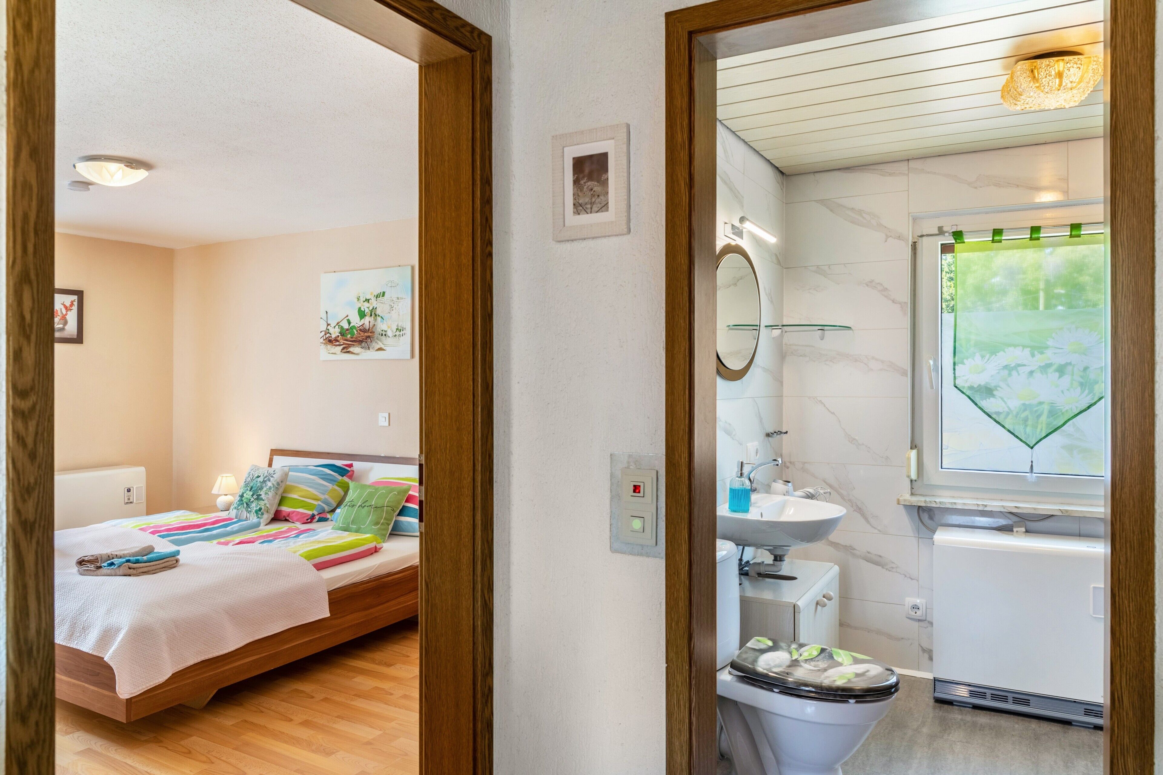 Een slaapkamer met een bed, kussens en een nachtkastje.