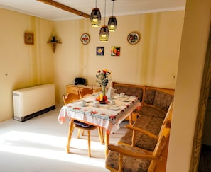 A dining area with a table set for four, a radiator, and a wooden bench. - Vacation Home "Ulbrich" with Private Terrace, Balcony & Wi-Fi (Neudrossenfeld)