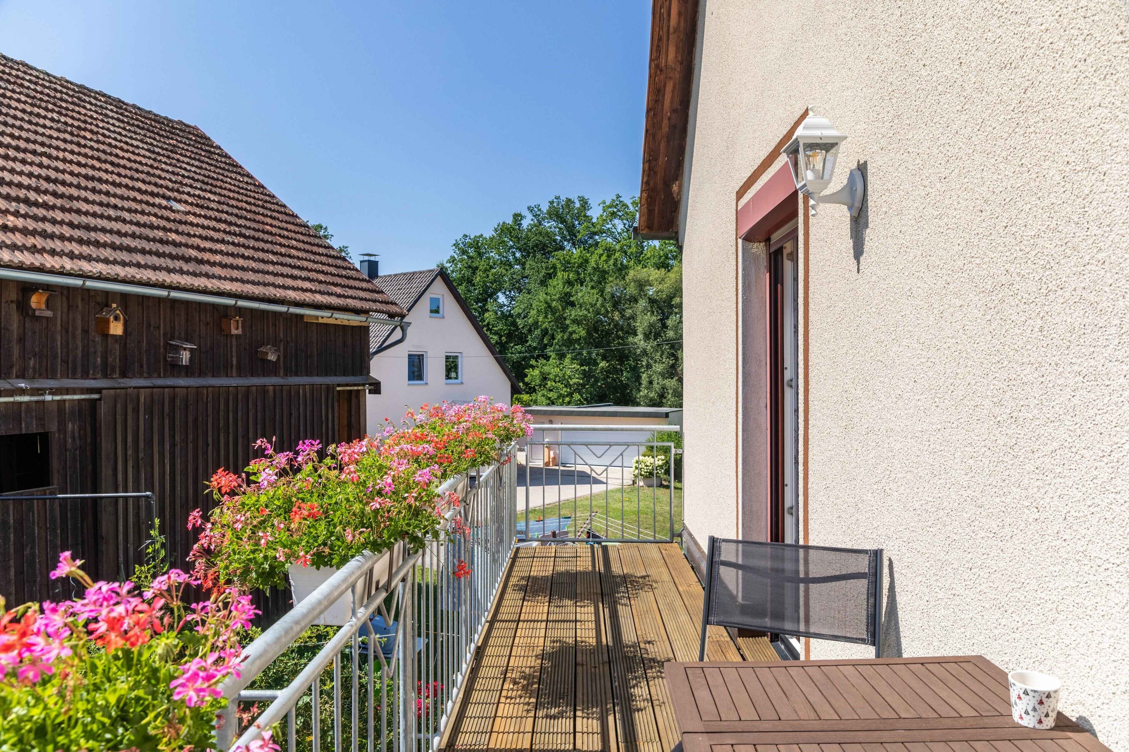 Een balkon met uitzicht op een traditioneel huis en een houten schuur.