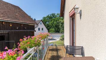 Een balkon met uitzicht op een traditioneel huis en een houten schuur.