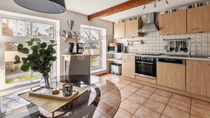 A modern kitchen with wooden cabinets, a large window, and a dining area with a table and chairs. - Apartment 'Ferienwohnung Obenauf' with Private Terrace and Wi-Fi (Oesterwurth)
