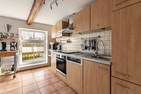 A modern kitchen with wooden cabinets, a stainless steel sink, and a window with a view of greenery. - Apartment 'Ferienwohnung Obenauf' with Private Terrace and Wi-Fi (Oesterwurth)