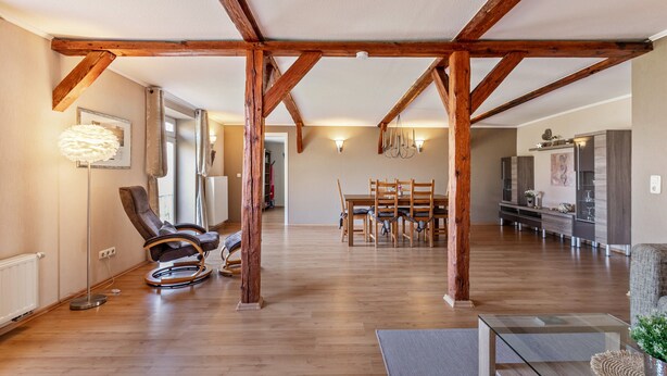 A spacious living area with wooden beams, a dining table, chairs, a sofa, and a television. - Apartment 'Ferienwohnung Obenauf' with Private Terrace and Wi-Fi (Oesterwurth)