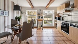 A modern kitchen with wooden beams, a glass dining table, and a view through large windows. - Apartment 'Ferienwohnung Obenauf' with Private Terrace and Wi-Fi (Oesterwurth)