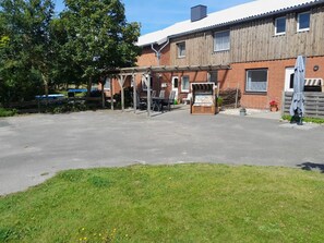 Een gebouw met een bakstenen gevel, een overdekt terras en een geplaveid toegangspad.