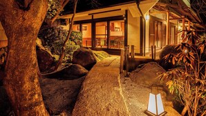 Una casa tradicional japonesa con fachada de madera, un sendero de piedra y un farol.
