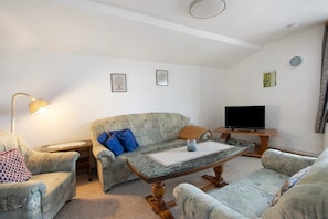 A living room with a sofa, armchairs, a coffee table, a TV, and a lamp. - Apartment 'Plüschmors' with Shared Garden, Balcony and Wi-Fi (Hedwigenkoog)