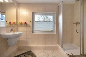 Ein Badezimmer mit Waschbecken, Spiegel, Fenster und Dusche.