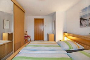 A bedroom with a bed, a desk, a chair, a wardrobe, and a door. - Apartment 'Plüschmors' with Shared Garden, Balcony and Wi-Fi (Hedwigenkoog)