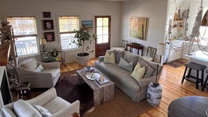Un salon spacieux comprenant un canapé, des fauteuils, une table basse et un coin repas avec une table et des chaises.