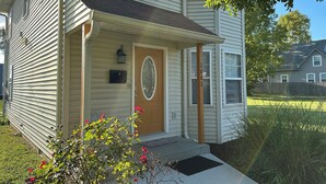 Une maison à deux étages avec un porche à l’avant, une boîte aux lettres et une porte ornée d’un panneau de verre décoratif.