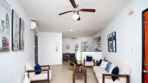 A spacious living room with a ceiling fan, a sofa set, a coffee table, and a dining area in the background.