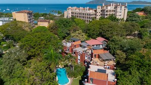 A large building with multiple balconies and a swimming pool surrounded by lush greenery.