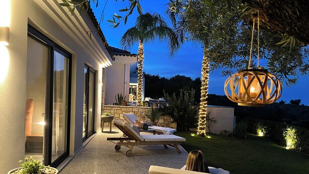Eine Terrasse mit Liegestühlen, einem Topfpflanzen und einer hängenden Laterne.