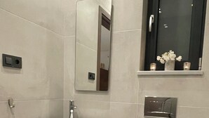 Ein modernes Badezimmer mit Waschbecken in Weiß, einer schwarzen Ablage und einer weißen Toilette.