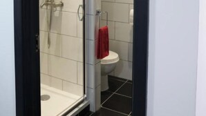 Una cabina doccia in vetro con un water bianco e un asciugamano rosso appeso al muro.