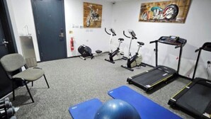 Una palestra con attrezzature per esercizi, una palla da ginnastica blu e un tapis roulant.