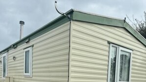 A single-story mobile home with a sloped roof, a window, and a small attached garage.