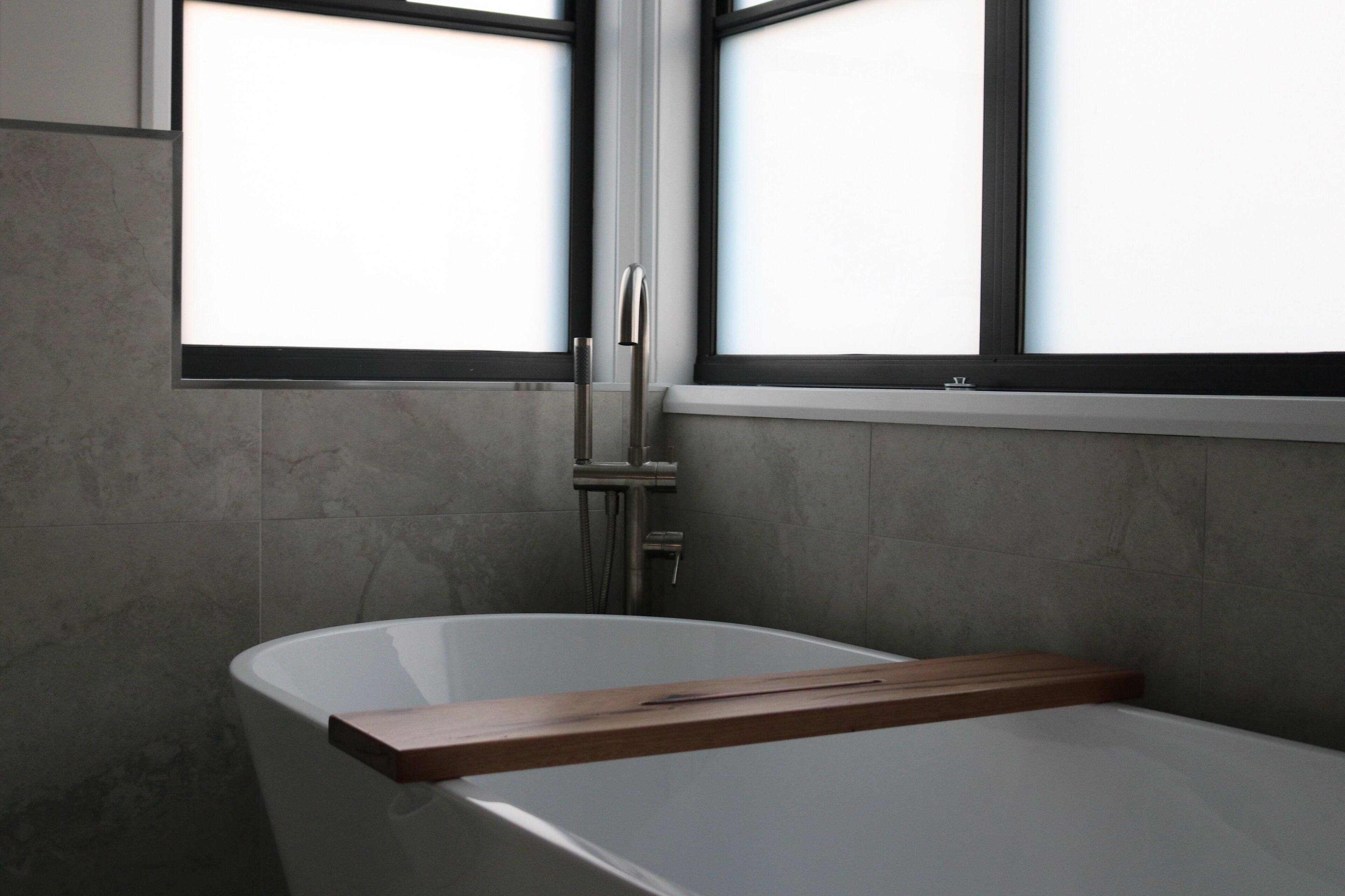 Un baño moderno con una bañera independiente, un ventanal con marco negro y un perchero.