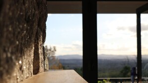 Une table en bois donnant sur un paysage montagneux, visible à travers une fenêtre.