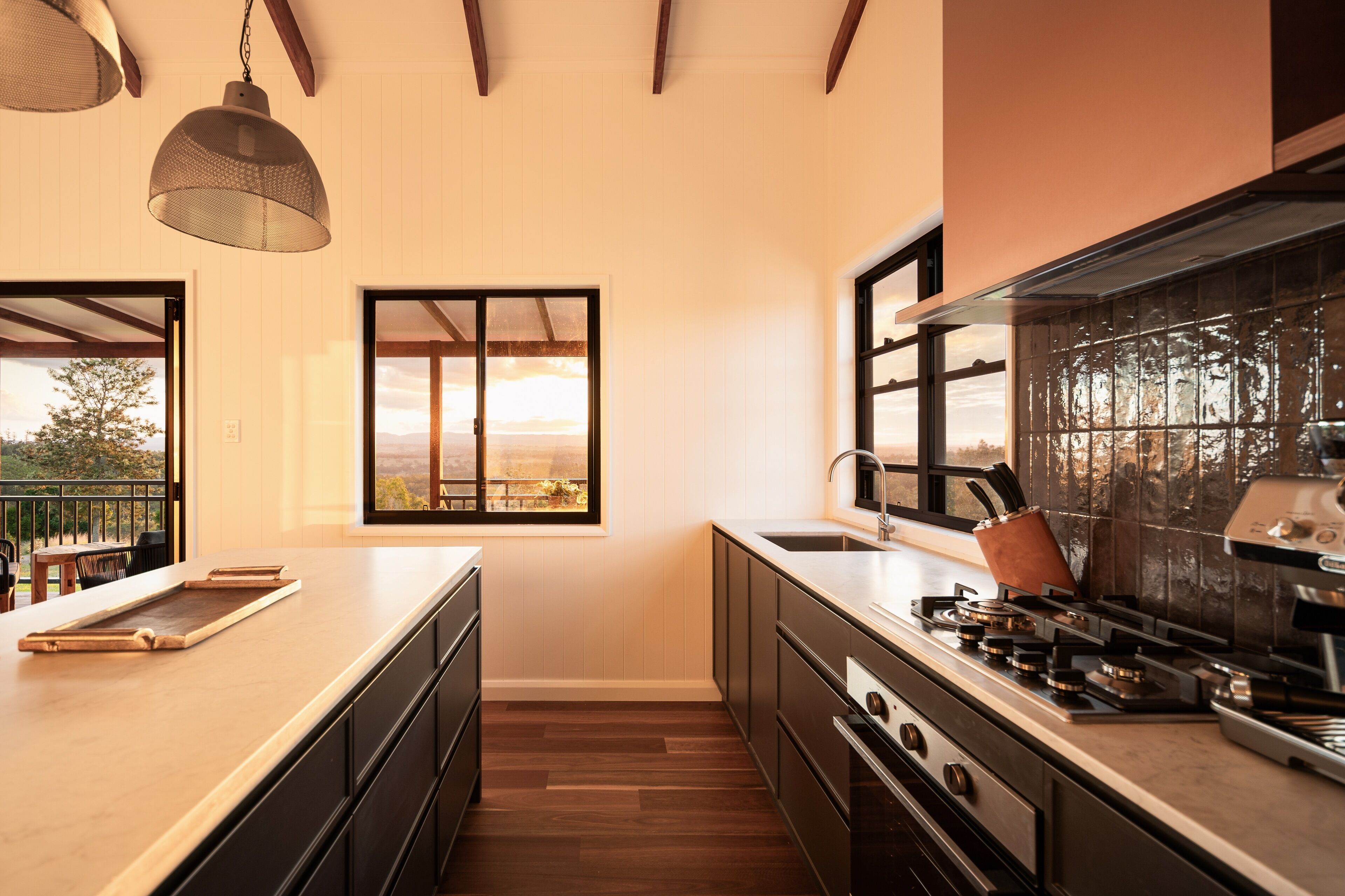 Uma cozinha moderna com piso de madeira, uma ilha grande e vista para o exterior através de uma janela.