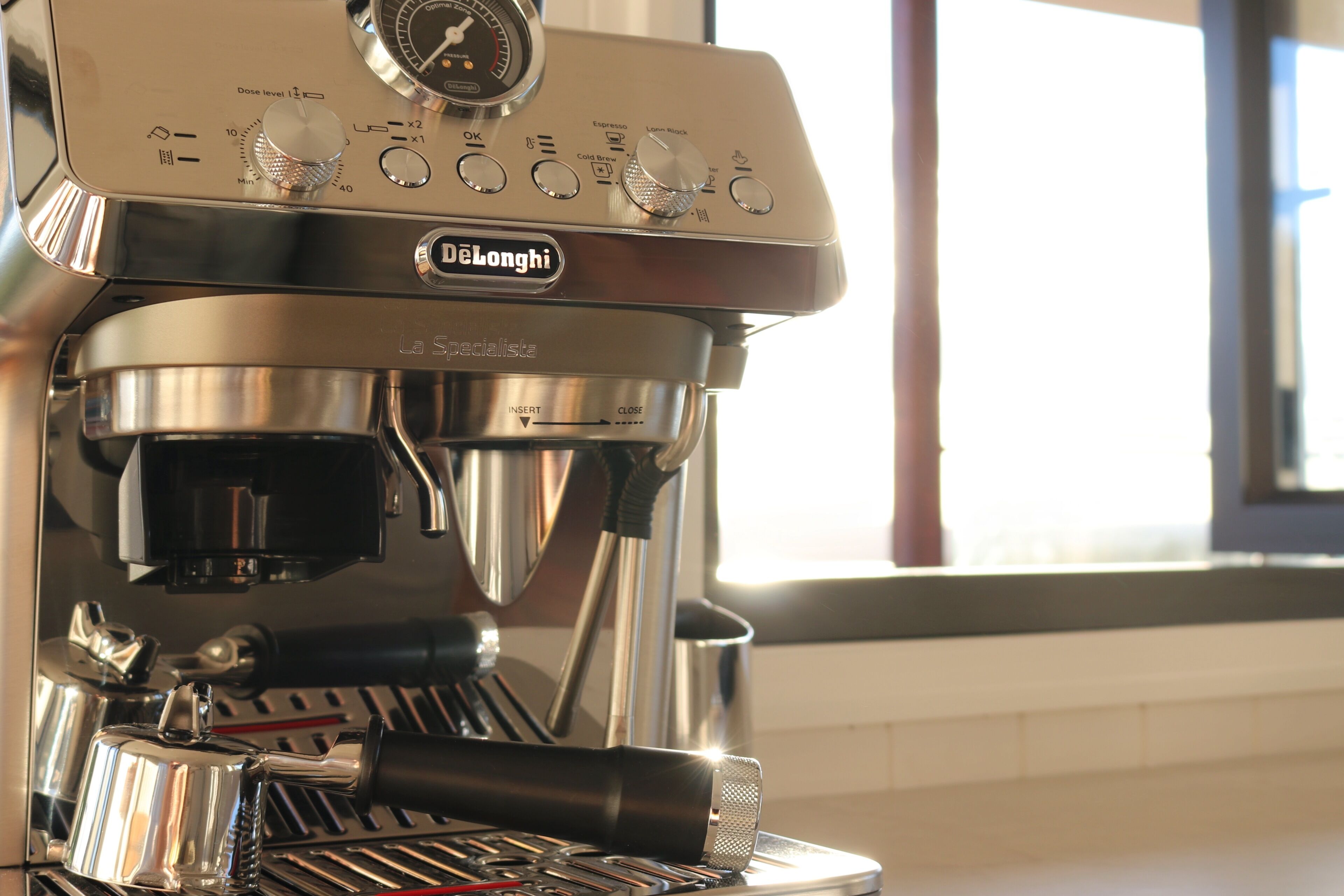 A DeLonghi La Specialista espresso machine with a digital display, a portafilter basket, and a drip tray.