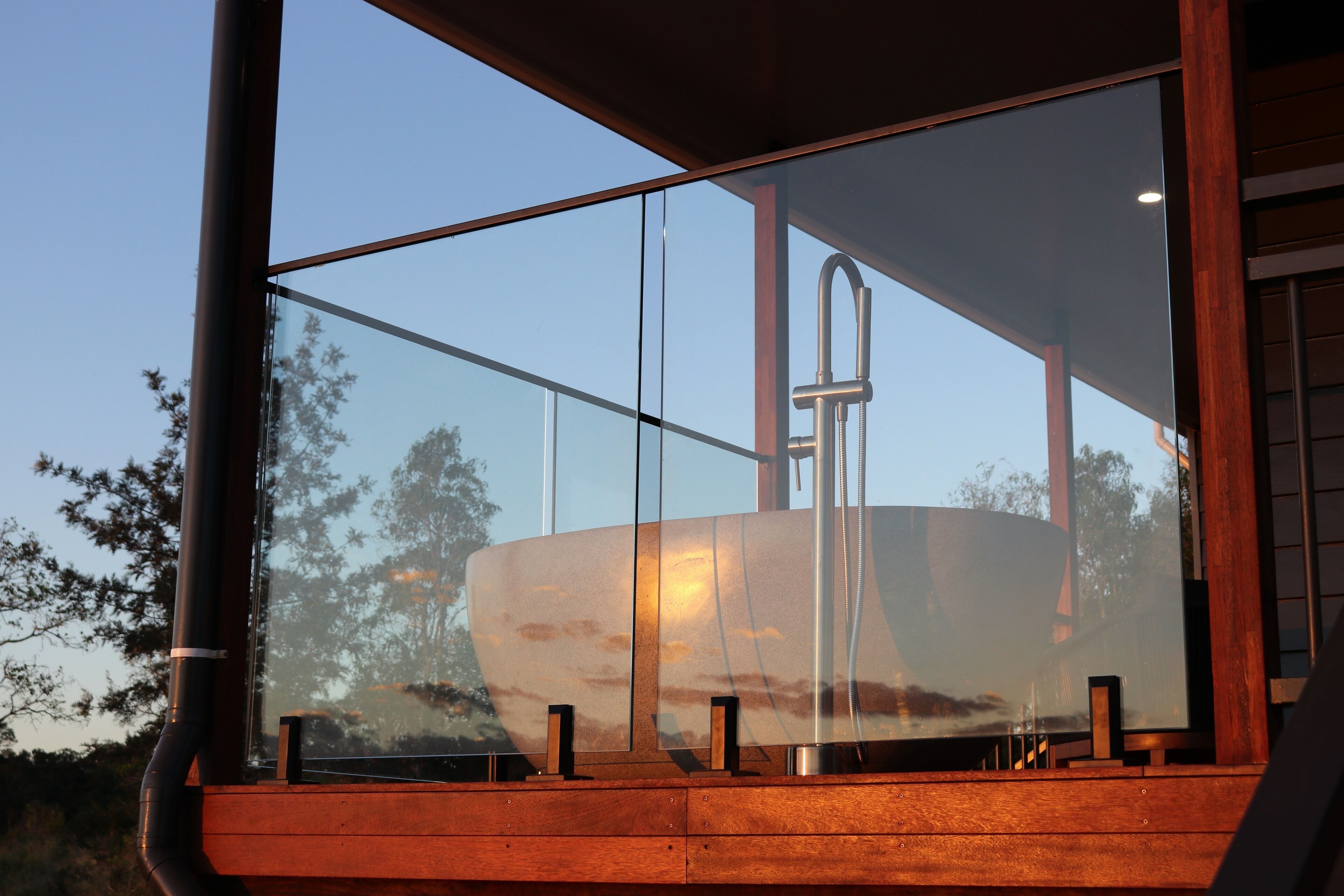 Un edificio moderno con amplios ventanales que reflejan el atardecer y un barco.