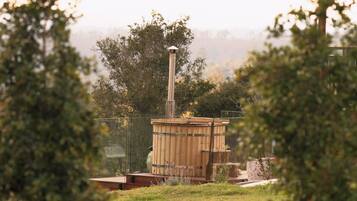 A sauna structure with a chimney, surrounded by greenery.
